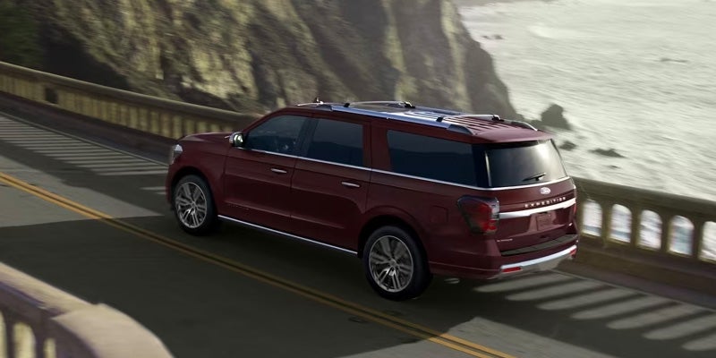 Red 2024 Ford Expedition MAX driving down a coastal highway while the sun begins to set