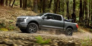 2024 Ford F-150 Lightning driving on off-road terrain.